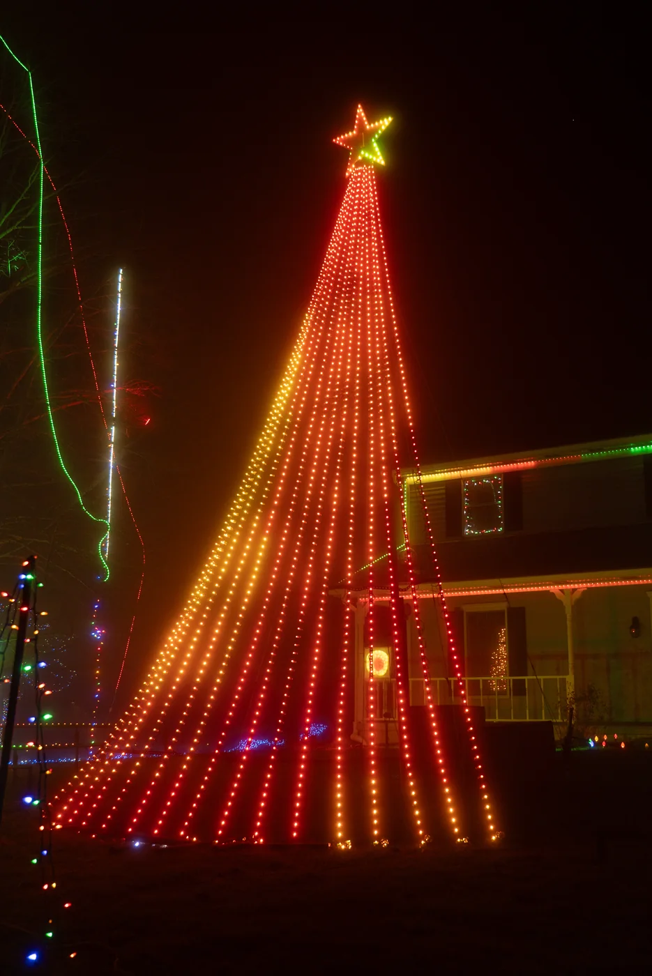 Tall Christmas light tree glowing in warm amber at night
