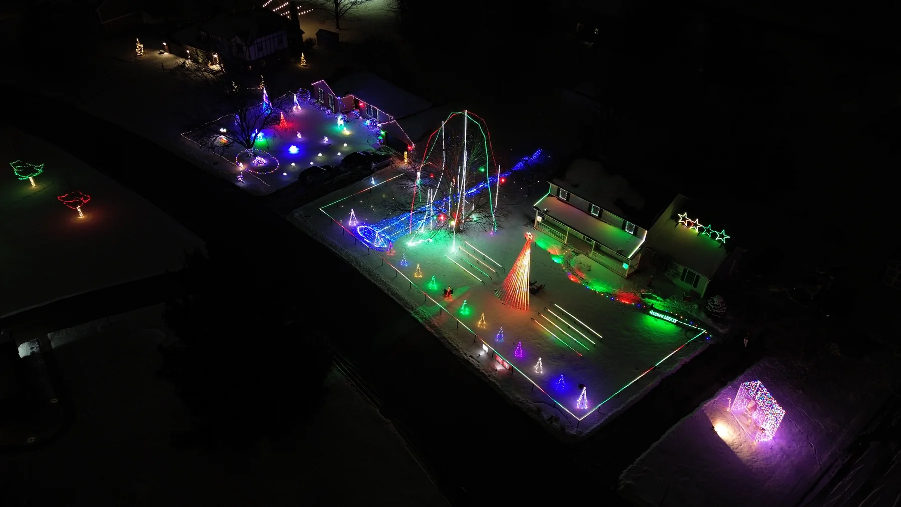 Aerial view of a colorful Christmas light display across a house and lawn