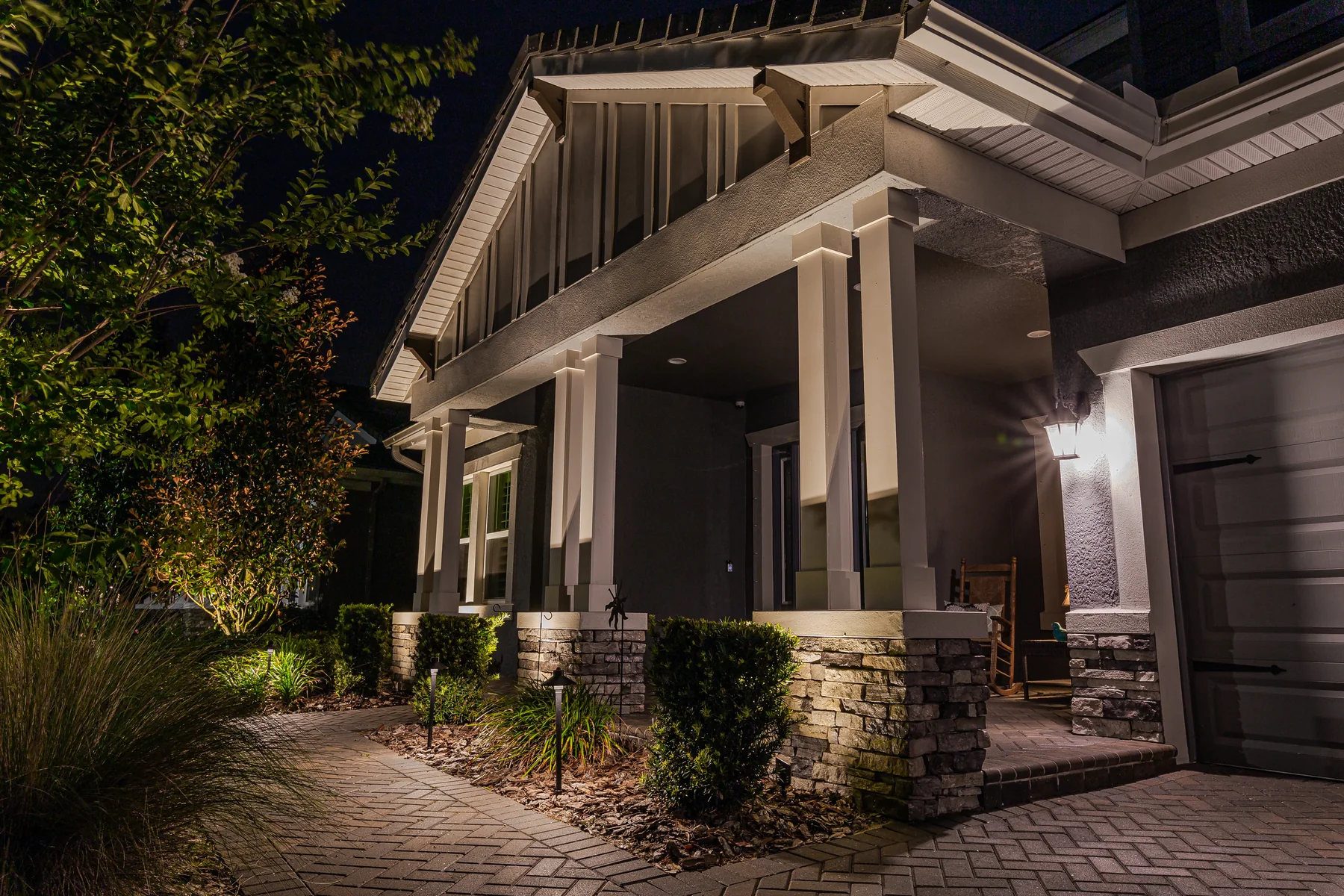 Warm architectural lighting on a home porch, columns and front path