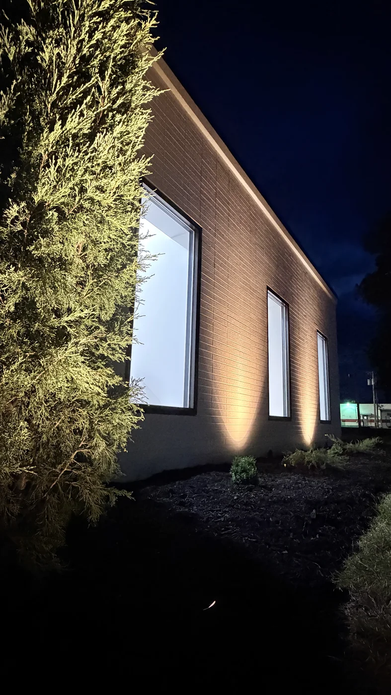 Uplighting along the brick facade and evergreen planting at Wharton Dental